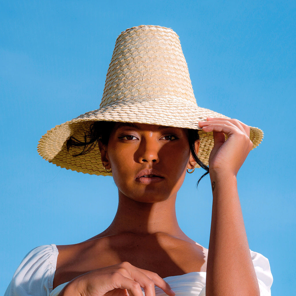 BrunnaCo Kemala Woven Straw Hat made for summer beach season. Crafted from lightweight natural palm straw, KEMALA hat has a high crown and wide down-turned brim to safely protect from the sun’s harsh rays.