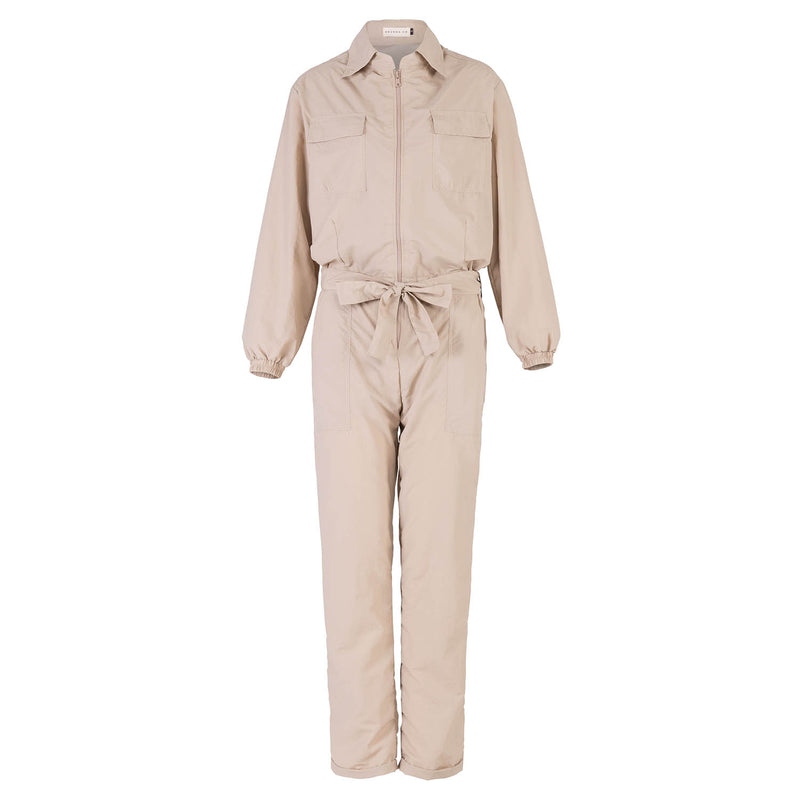 Our cool and casual Amelia Recycled Jumpsuit in sand beige with its relaxed style is designed for the perfect traveling or outdoor vacation. Complete with a spread collar, tie waist, and front utility pockets, this chic jumpsuit offers a simple yet stylish look.