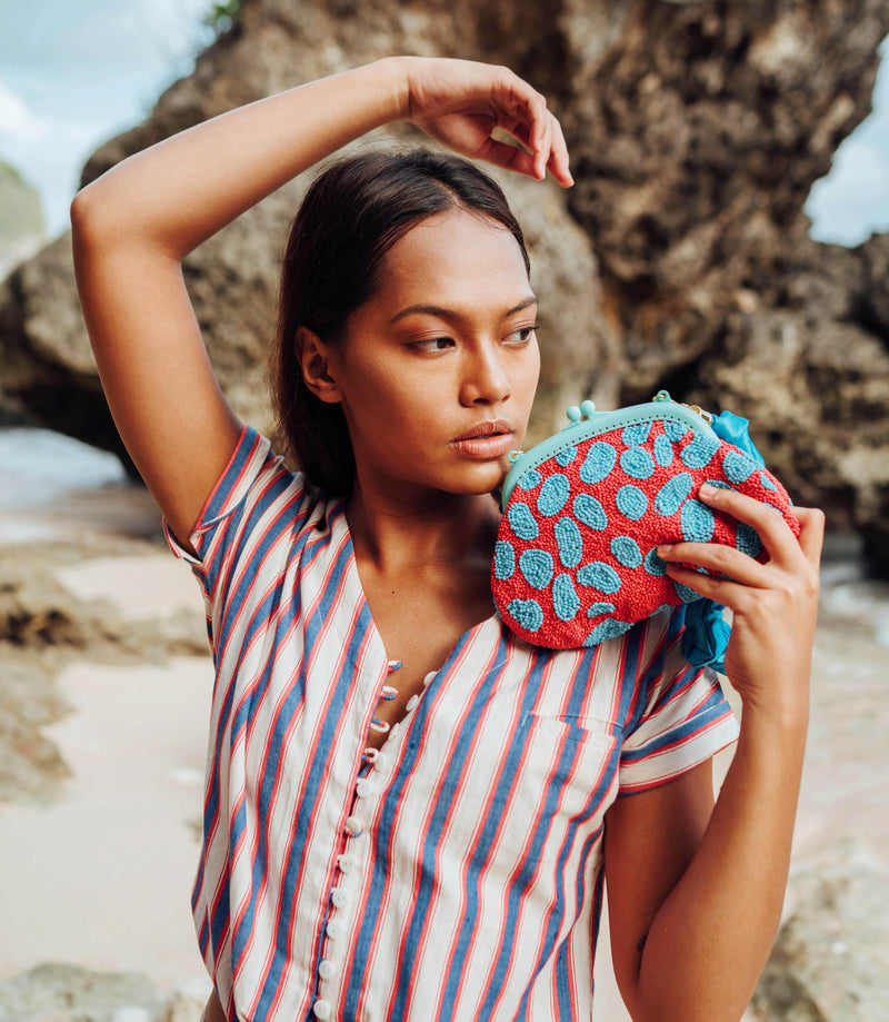 BrunnaCo Arnoldi Ariela Handbeaded clutch in red and turquoise blue color is an artisanal handmade piece by female artisans in Bali. This handbag clutch is carefully and sustainably made using glass beads in playful polka dot pattern.