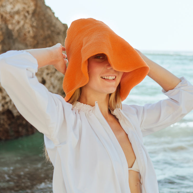BrunnaCo Bloom Crochet Hat in pumpkin orange color. Soft and shapeable crochet hat inspired by the classic Calla Lily flower shape. Meticulously made by artisans in the villages of Bali. Its light and semi-floppy construction make it the perfect hat for picnics at the beach or poolside any season of the year.