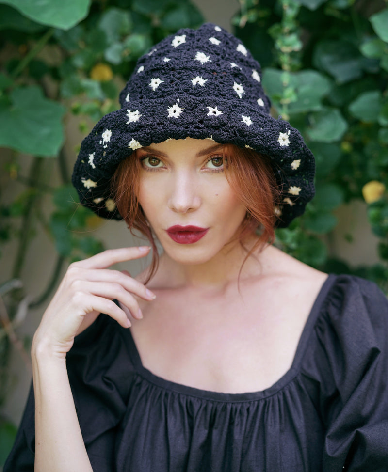 Flora Crochet Hat in Black. This gorgeous crochet hat made from 100% cotton yarn, complete with an eye-catching flower pattern, is designed to give you a fun and feminine fit.  A must-have collection for creating a cute and casual look. Hand-crocheted with love by our female artisans from their very own home in Bali.