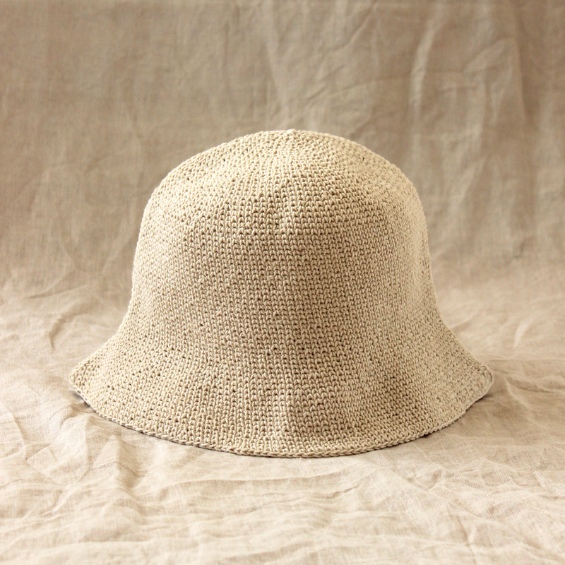 A woman is wearing BrunnaCo Florette Crochet hat in off white color. Florette crochet hat is a comfortable beach summer hat that is foldable and perfect to bring to any summer vacations
