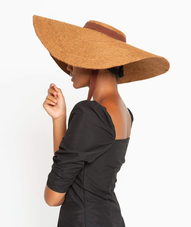 Lola Wide Brim Jute Straw Hat In Havana Brown. Braided meticulously by artisans in Gianyar, Bali from natural Jute material, this sweet hat offers both comfort and elegance. Designed with ideal thickness and weight that allow its brim to be easily folded, stretched, and styled, making it easy to take to any holiday trips or summer vacation.