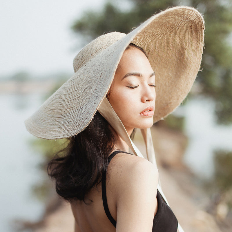 Lola Wide Brim Jute Straw Hat In Natural Beige. This sun hat is hand-weaved meticulously by women artisans in Gianyar, Bali from natural Jute material, this sweet hat offers both comfort and elegance. Designed with ideal thickness and weight that allow its brim to be easily folded, stretched, and styled, making it easy to take to any holiday trip. 