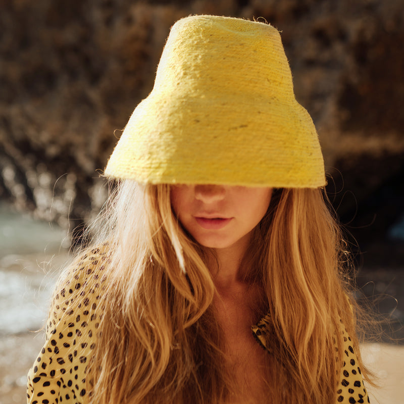 NAOMI Jute Straw hat in Yellow. Naomi Jute Bucket Hat is designed specifically for the wild at heart with classic sophistication. Enjoy lounging poolside or exploring the city on sun-soaked days as its protective hat brim provides ample shade. Made of natural jute straws which have the perfect weight, this hat will sit comfortably and won't fly away in sudden gusts. It's also very practical to pack in any size luggages and ideal to take on any trips.