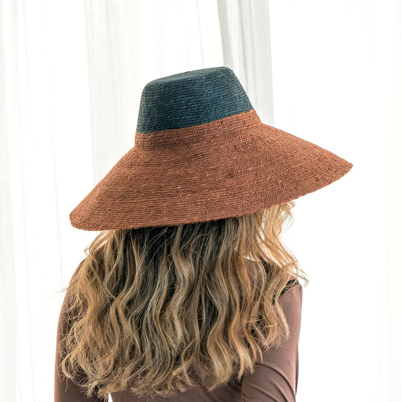 RIRI DUO Jute Straw Hat in Burnt Sienna & Black. Riri 'Duo' hat is perfect for packing on your next tropical vacation. It's made from the union of burnt sienna and black colors that are bold yet versatile. Handmade by our women artisans in Bali from natural jute straws, it has a sculpted crown and a brim that shields from the sun.