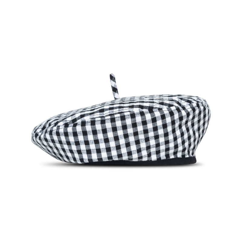 A woman is wearing BrunnaCo Simone Beret hat and she's ready for a casual stroll at the beach. The parisian beret hat has gingham pattern in black and white color